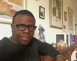 A Black Cuban man sitting amid Afro-Cuban photos and books