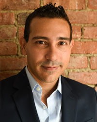 A man in a suit in front of a brick background