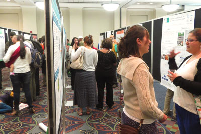 A crowded room of people viewing a conference poster session