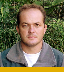 A man standing in a forest wearing casual clothes for the outdoors